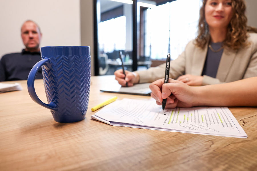 employees make notes on a market research report while discussing the insights