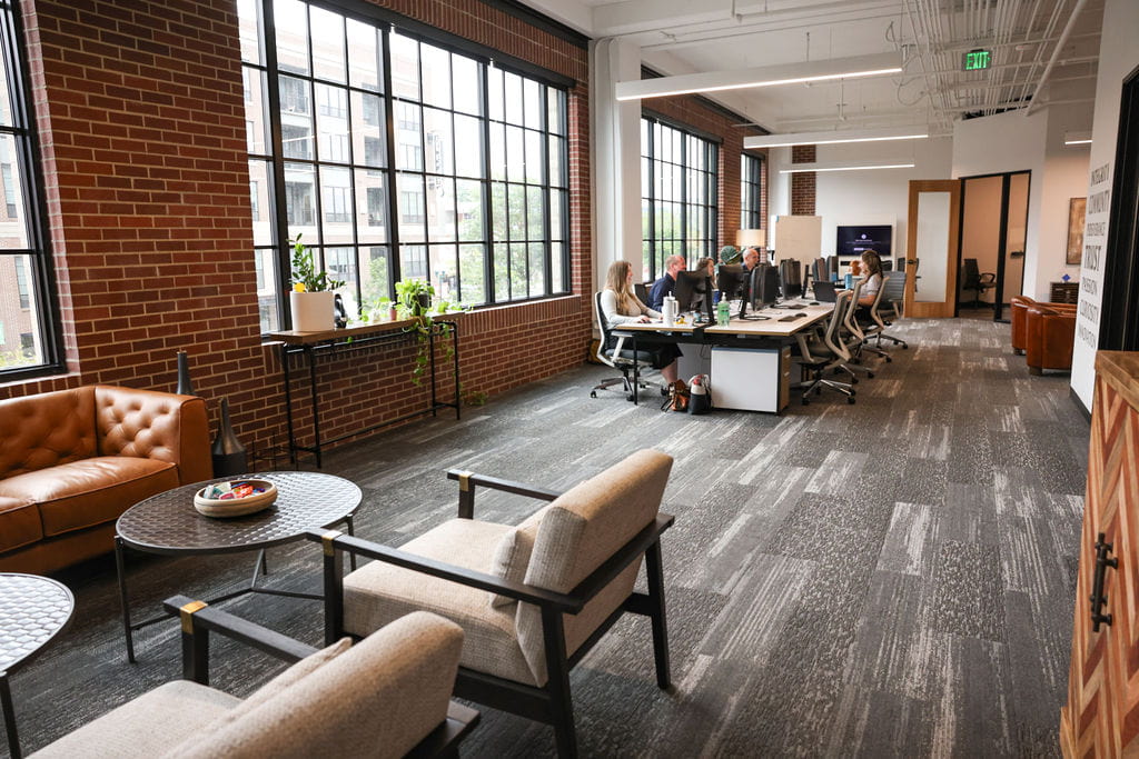 SMARI office with open windows, brick walls, and a long desk with 6 employees working at their stations