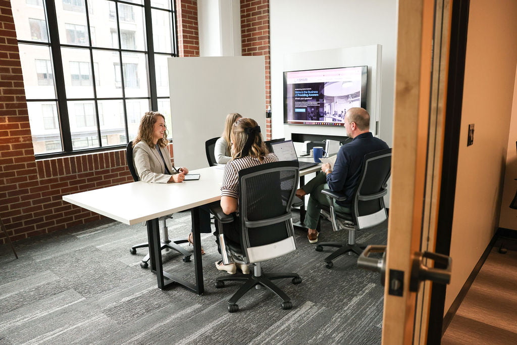 4 employees smiling at a meeting in the conference room