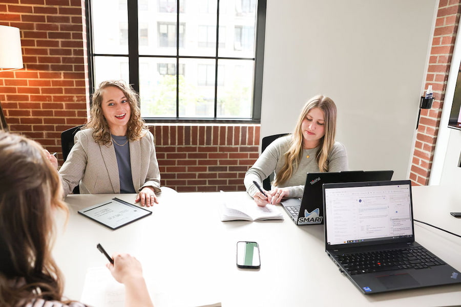 3 employees discussing market research at a conference room table while taking notes