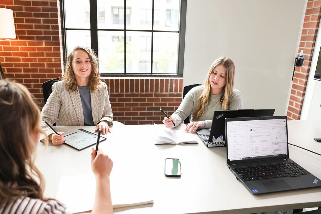 3 female employees working with laptops and tablets at a conference room