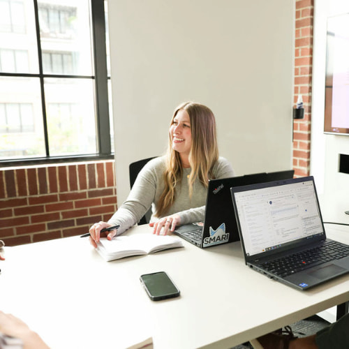 SMARI employee smiles from behind her laptop while at a meeting