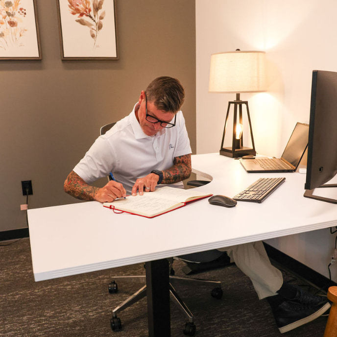 Male employee makes notes in his office in front of his computer