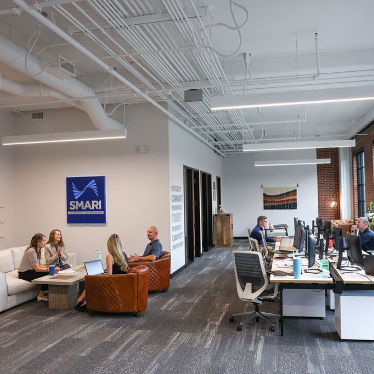 Candid employees working in the SMARI office at different desks, couches, and chairs