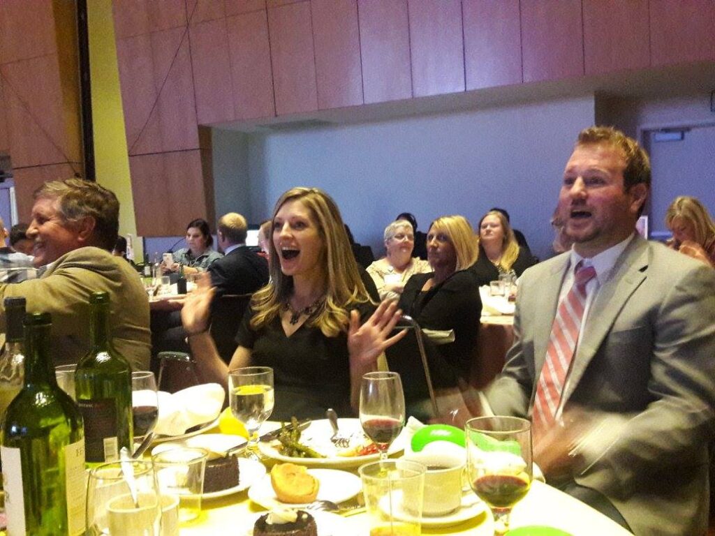 3 excited and smiling SMARI employees at a conference dinner