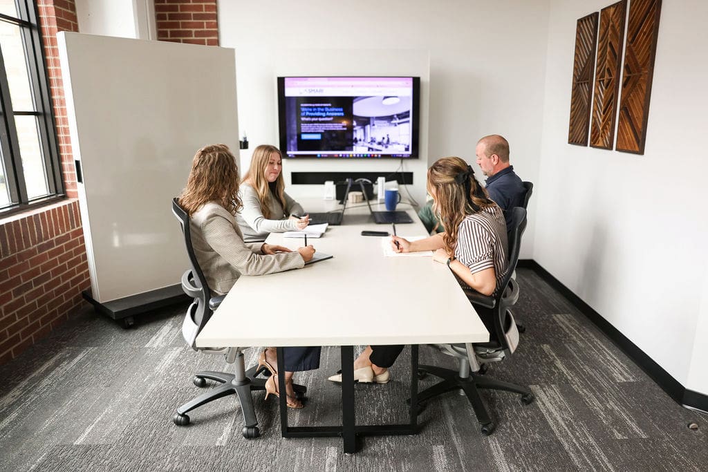 4 employees working together and smiling in a conference room